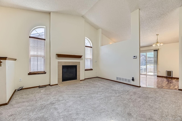 17692 E Brown Cir, Aurora, CO 80013 - unfurnished living room featuring a textured ceiling, a tiled fireplace, carpet flooring, high vaulted ceiling, and a chandelier