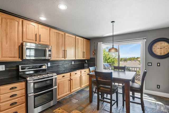 7243 S Kellerman Way, Aurora, CO 80016 - kitchen featuring stainless steel appliances, backsplash, stone tile flooring, dark countertops, and a textured ceiling