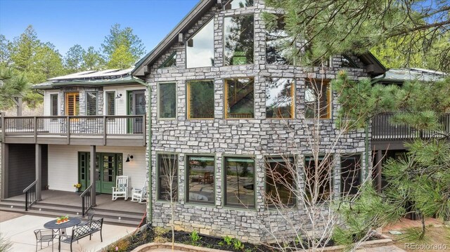 7317 Fremont Pl, Larkspur, CO 80118 - rear view of property featuring a wooden deck, stone siding, and a balcony