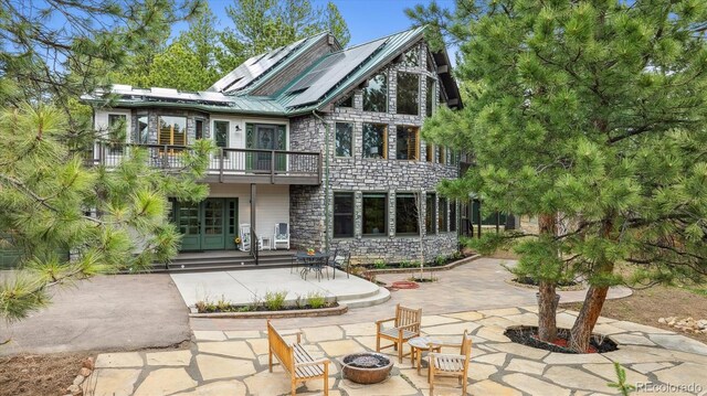7317 Fremont Pl, Larkspur, CO 80118 - rear view of house with stone siding, a balcony, an outdoor fire pit, and french doors