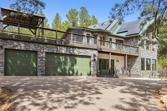 7317 Fremont Pl, Larkspur, CO 80118 - exterior space featuring solar panels, driveway, stone siding, a garage, and a balcony
