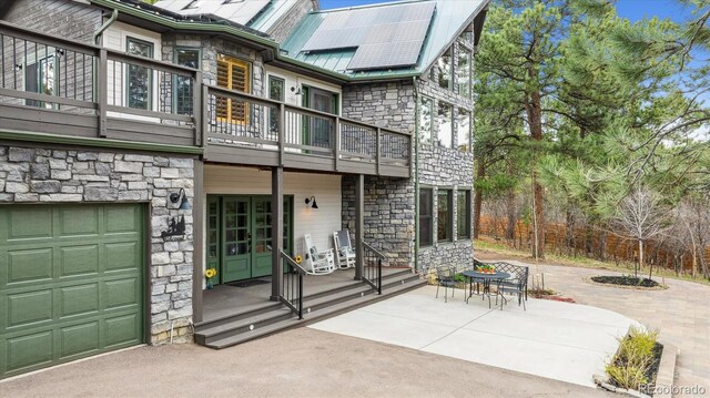 7317 Fremont Pl, Larkspur, CO 80118 - exterior space featuring metal roof, stone siding, a balcony, and a garage