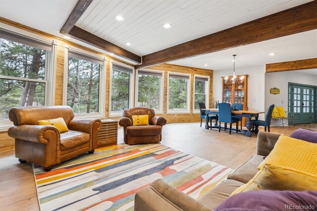 7317 Fremont Pl, Larkspur, CO 80118 - living area with plenty of natural light, wood finished floors, beam ceiling, and a notable chandelier