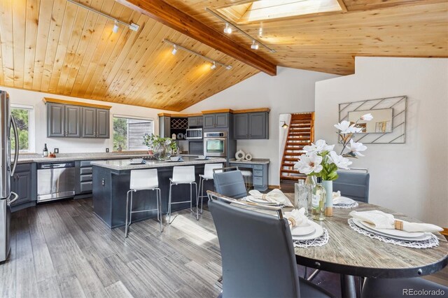 7317 Fremont Pl, Larkspur, CO 80118 - dining space featuring wooden ceiling, lofted ceiling with skylight, rail lighting, and dark wood finished floors