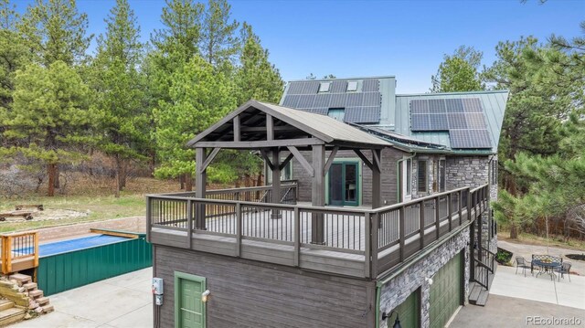 7317 Fremont Pl, Larkspur, CO 80118 - rear view of house featuring stone siding, a gazebo, and metal roof