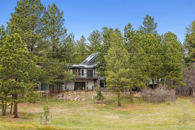 7317 Fremont Pl, Larkspur, CO 80118 - back of house featuring a lawn, a deck, a wooded view, and solar panels