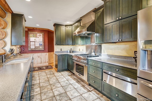 kitchen with appliances with stainless steel finishes, wall chimney range hood, sink, and tasteful backsplash