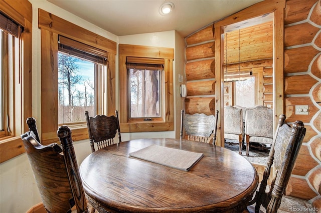 dining area featuring lofted ceiling and log walls