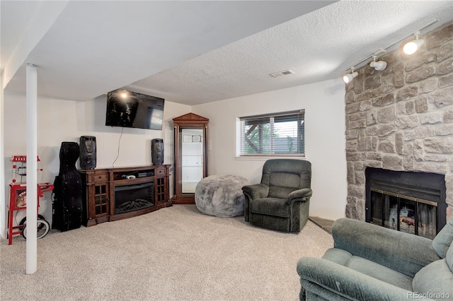 living area featuring a fireplace, carpet flooring, a textured ceiling, and track lighting