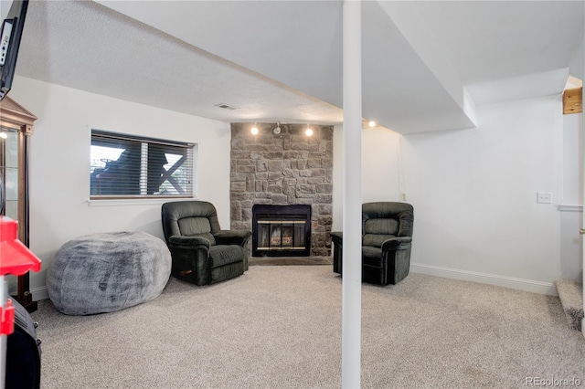 basement with carpet flooring, a stone fireplace, and baseboards