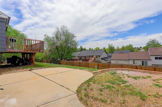 view of yard featuring fence, a residential view, a deck, and a patio