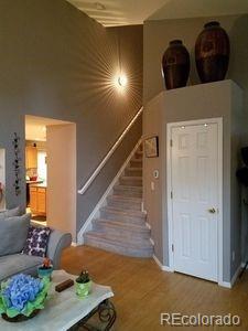 living room featuring a towering ceiling, baseboards, stairway, and wood finished floors