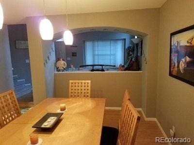 dining space featuring arched walkways, baseboards, and vaulted ceiling