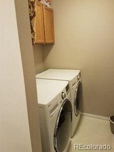 clothes washing area featuring cabinet space, baseboards, and separate washer and dryer