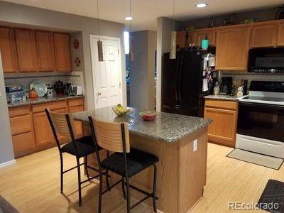 kitchen with light wood finished floors, a breakfast bar, a center island, brown cabinets, and black appliances
