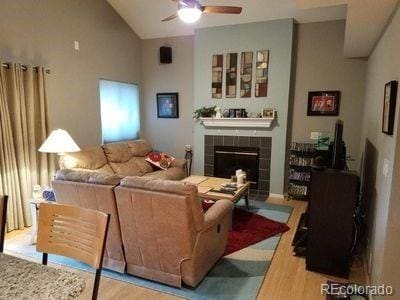 living room with lofted ceiling, ceiling fan, a tile fireplace, and wood finished floors