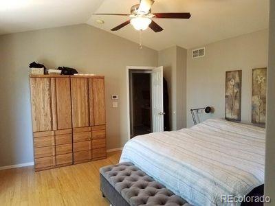 bedroom with light wood finished floors, baseboards, visible vents, and vaulted ceiling