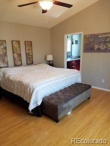 bedroom featuring ensuite bath, lofted ceiling, ceiling fan, and wood finished floors