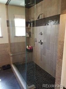 bathroom with tile patterned floors, tile walls, and a shower stall