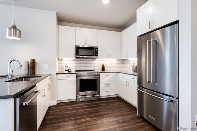 kitchen featuring dark countertops, white cabinets, decorative light fixtures, and high quality appliances