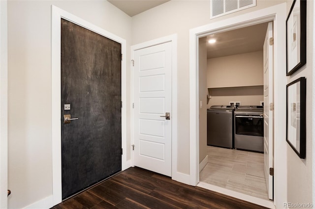 hallway with dark wood-style floors, baseboards, visible vents, and washer and dryer