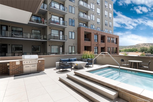 view of swimming pool featuring a fire pit, an outdoor kitchen, a patio, a community hot tub, and a mountain view