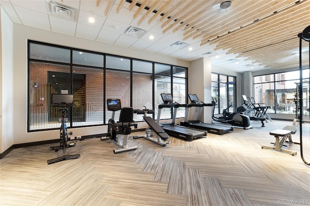 exercise room featuring visible vents, light carpet, and baseboards