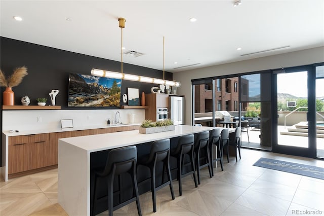 kitchen featuring open shelves, brown cabinetry, light countertops, and visible vents