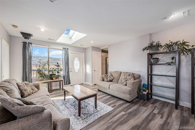 living area featuring a skylight, baseboards, and wood finished floors