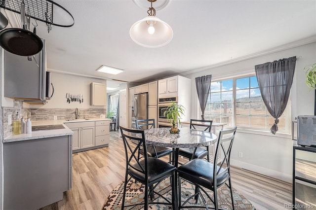 dining space featuring crown molding, light wood-type flooring, and baseboards