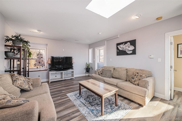 living area with a skylight, baseboards, and wood finished floors