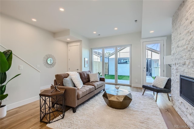 living room featuring a stone fireplace and light hardwood / wood-style flooring