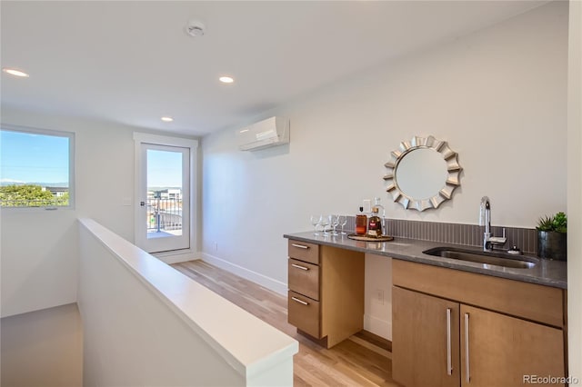 bar with a wall mounted air conditioner, light wood-type flooring, and sink