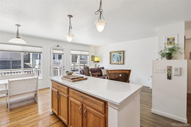 588 Beauprez Ave, Lafayette, CO 80026 - kitchen featuring light wood-style floors, decorative light fixtures, light countertops, brown cabinetry, and a textured ceiling