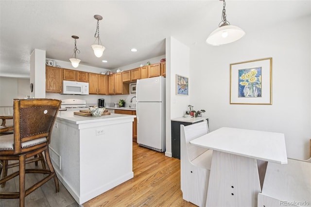 588 Beauprez Ave, Lafayette, CO 80026 - kitchen featuring white appliances, light countertops, light wood-type flooring, a kitchen breakfast bar, and hanging light fixtures
