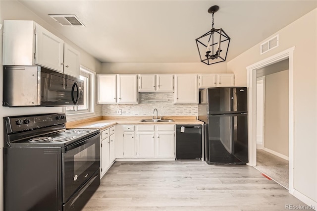 kitchen featuring pendant lighting, black appliances, white cabinets, sink, and a notable chandelier