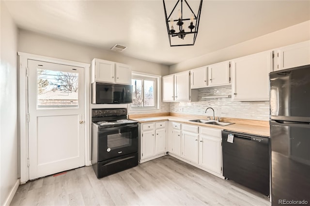 kitchen with sink, a chandelier, light hardwood / wood-style floors, white cabinets, and black appliances