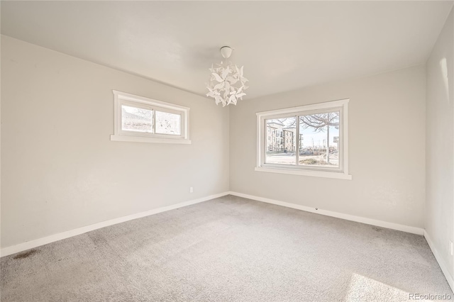 carpeted empty room with a notable chandelier