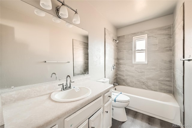 full bathroom with hardwood / wood-style floors, vanity, toilet, and tiled shower / bath