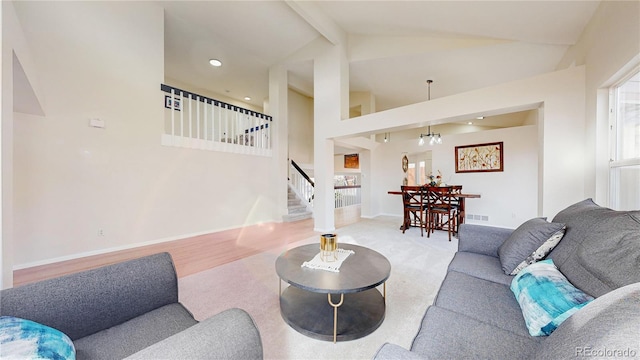 living room with lofted ceiling with beams and an inviting chandelier