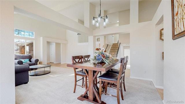 carpeted dining room with a towering ceiling and an inviting chandelier