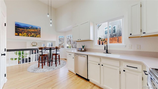 kitchen featuring stainless steel dishwasher, sink, pendant lighting, range, and white cabinetry