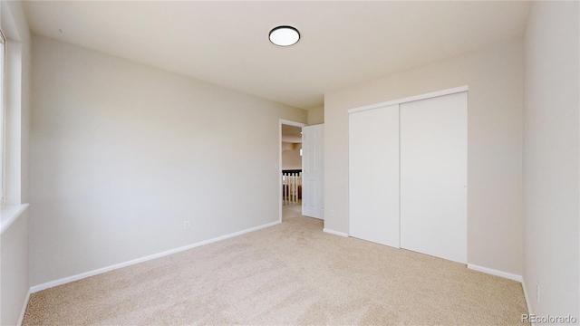 unfurnished bedroom featuring light carpet and a closet