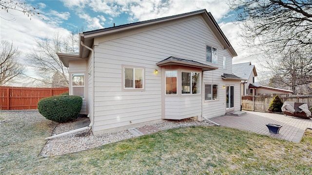 rear view of house featuring a lawn and a patio