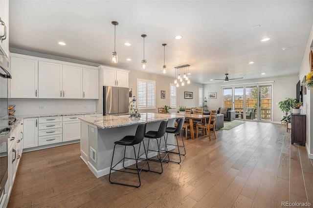 kitchen with stainless steel fridge, a kitchen breakfast bar, a kitchen island, and white cabinets