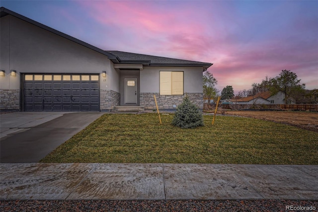 view of front of home with stone siding, stucco siding, concrete driveway, an attached garage, and a yard