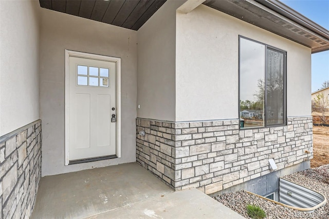 property entrance with stucco siding and stone siding