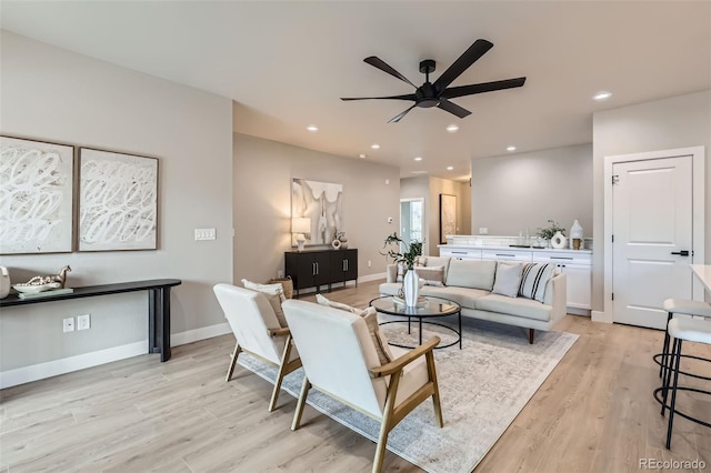 living area featuring light wood-type flooring, a ceiling fan, baseboards, and recessed lighting