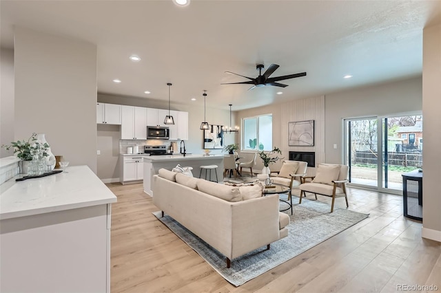 living room featuring recessed lighting, ceiling fan, and light wood-style flooring