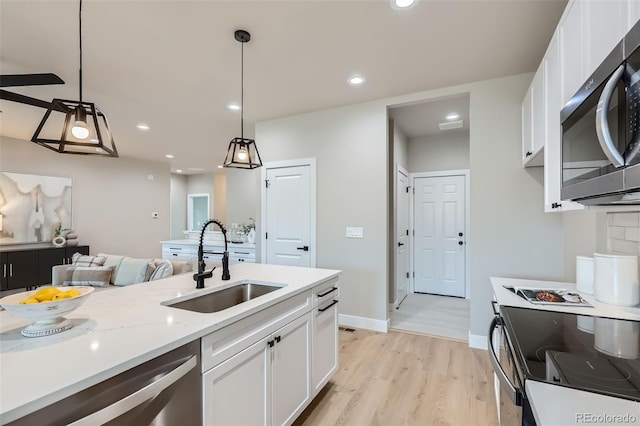kitchen featuring stainless steel appliances, white cabinetry, a sink, and light wood-type flooring
